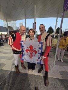 Due sbandieratori dei Bandierai degli Uffizi donano il foulard del gruppo a un'organizzatrice al Kai Tak Stadium di Hong Kong